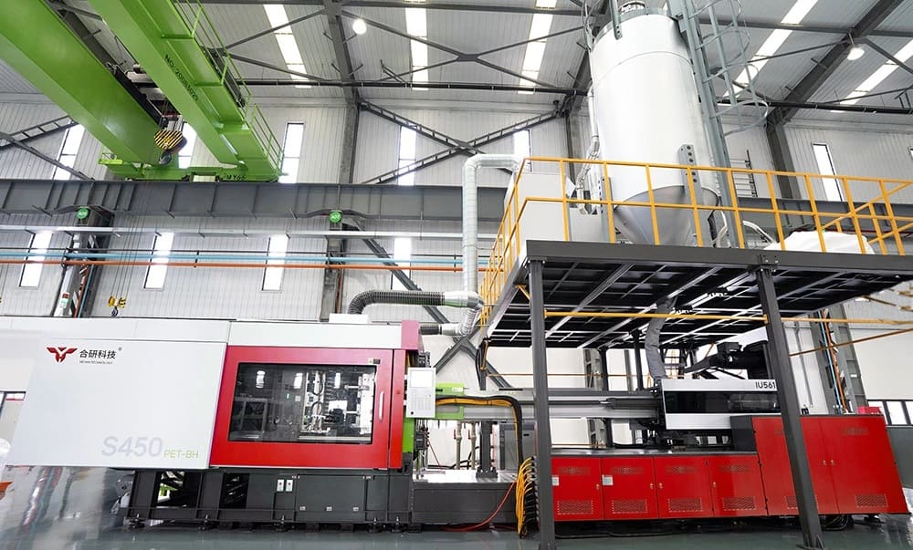 Large industrial plastic injection molding machine operating inside a modern factory facility